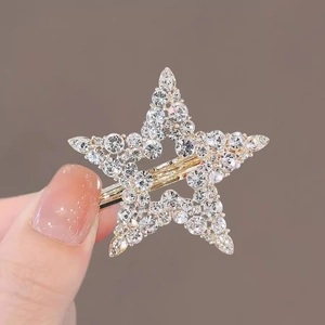 Detailed view showing the small size of a gold star hair claw clip with crystals