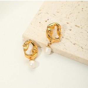 Macro view of gold plated irregular lava earrings with hanging white freshwater pearls