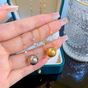 Close-up of minimalist gold and silver polished ball pendants on thin neck chains