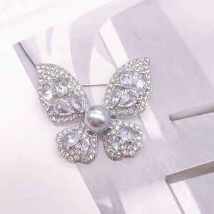 Broche papillon argentée raffinée avec cristaux brillants et une perle grise centrale