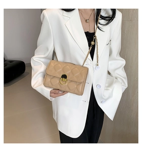 Detail of beige quilted leather crossbody bag with vintage gold buckle and chain strap