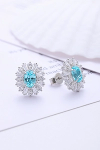 Dettaglio macro di orecchini a lobo in argento S925 con gemma blu e design floreale
