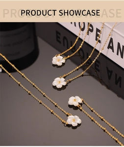 Detail of 18K gold plated necklaces with shell flower pendants on reflective surface