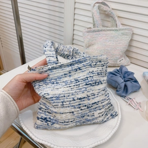 Dettaglio mini borsa in tweed pastello con cerniera ed etichetta tessuta su un piatto