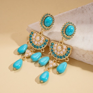 Macro view of vintage gold earrings with turquoise stones and faux pearls in artistic setting