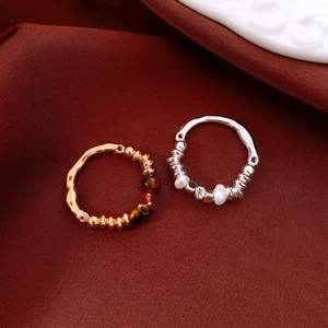 Detailed close-up of tiger eye and pearl beaded rings with textured 18K gold plating