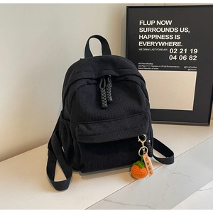 Close-up of black corduroy mini backpack with woven orange persimmon charm detail