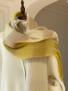 Close-up of thick gradient checkered scarf with tassels on white knit sweater