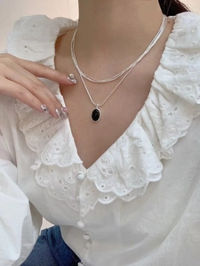 Detail of layered silver snake chain with oval black onyx pendant on a female model