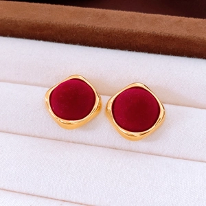 Detail of vintage gold square stud earrings with burgundy flocked center on cream velvet