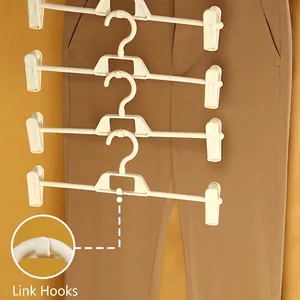Space-saving cream white plastic pants hangers with adjustable clips in a tiered hanging display
