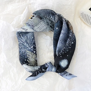 Detailed view of dark blue silk scarf with artistic snow night pattern tied on white paper
