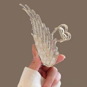 Detail of angel wing hair claw clip with rhinestones and opal-like stones in hand