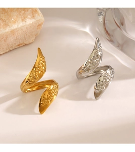 Detail of gold and silver spiral rings with floral relief on a stone and glass base