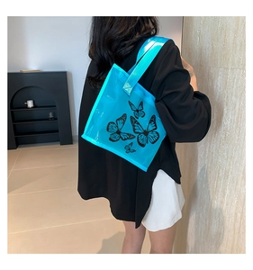 Detail view of blue transparent PVC tote bag featuring black butterfly print and glossy strap