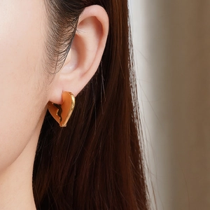 Minimalist gold broken heart stud earrings worn by a model in a professional close-up