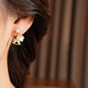 Close-up of a 14k gold plated horse earring with pearls and zircon on model's ear