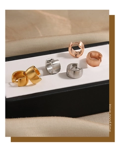 Detailed macro view of gold silver and rose gold brushed matte hoop earrings in a box