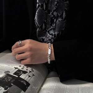 Detail of silver Cuban chain bracelet with rectangular plate on a vintage fashion magazine