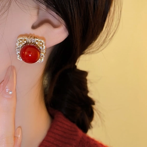 Close-up of vintage gold square earring with a large red stone and zircon pavé on model