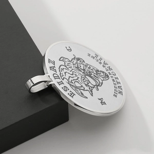 Macro detail of silver round medallion pendant with engraved lion motif and lettering