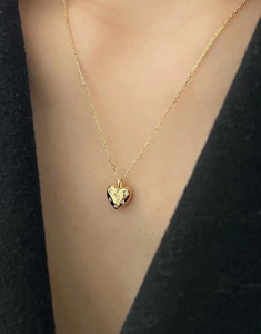 Vue macro d'un collier cœur en argent 925 doré serti de zircons sur le cou d'un mannequin