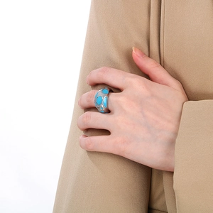 Detail of chunky silver stainless steel ring with blue enamel polka dots on fabric