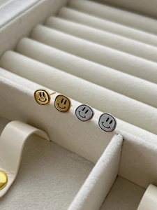 Détail de boucles d'oreilles smiley en argent et or sur une boîte en velours chic