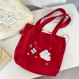Detail of red drawstring tote bag with cute rabbit embroidery and thick shoulder strap