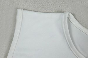 Détail de la texture en maille fine et des coutures renforcées d'une robe moulante blanche