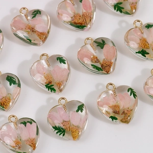 Detail of heart-shaped resin pendants with pink dried flowers and green leaves