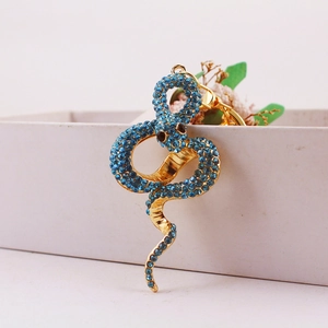 Kreativer goldener Schlangen-Schlüsselanhänger mit blauen Strasssteinen auf Geschenkbox