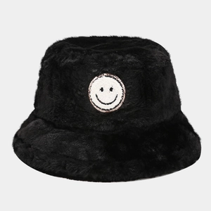 Close-up of black faux fur bucket hat featuring a white smiley face embroidered patch