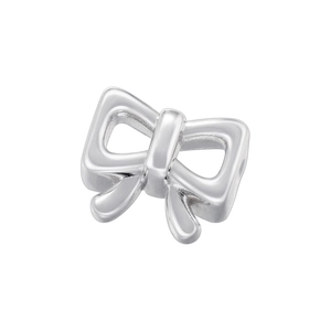 Macro shot of silver metal bow-shaped pendant showing smooth texture and metallic luster