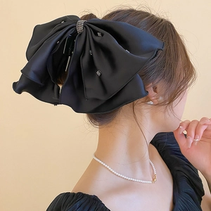 Détail d'une pince à cheveux en satin noir ornée de strass brillants et élégants