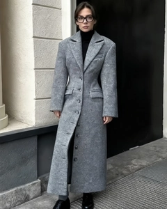 Dettaglio del cappotto di lana grigio con rever e pieghe eleganti in vita