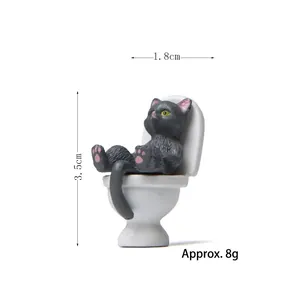 Funny black cat figurine sitting on a white toilet, creative resin miniature for desk decor
