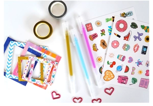 Detailed flat lay of DIY journal set with stickers, pens, washi tapes and paper frames