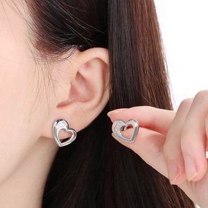 Detail shot of hollow heart silver earrings showing the 925 authenticity hallmark clearly