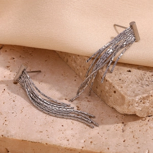 Silver chain tassel T-bar earrings on a beige stone background in a stylish still life shot