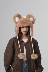 Detail of plush bear ear hat with brown faux fur texture and cute pompom drawstrings