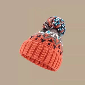Detailed view of winter knit beanie featuring colorful pom-pom and thick orange ribbed cuff