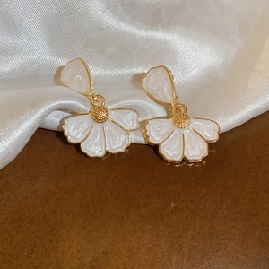 Détail de boucles d'oreilles en fleur avec pétales texturés marbre et cœur doré
