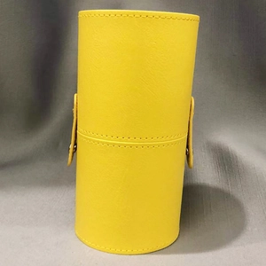 Detailed view of a yellow leather makeup brush holder with metal snap buckle closures
