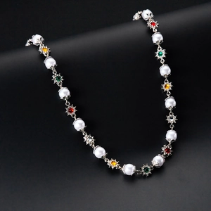 Detailed shot of pearl flower necklace with multicolored gemstones on black background