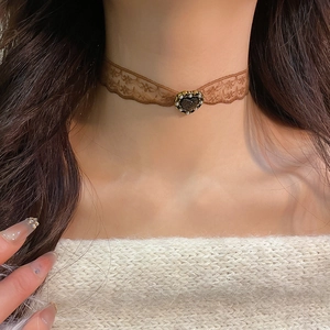 Detail of vintage brown lace choker with a black heart pendant and pearl trim on a model