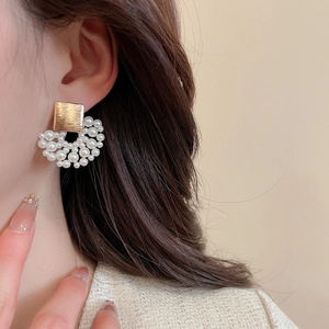 Detail of vintage gold square stud earrings with clustered white pearls on model