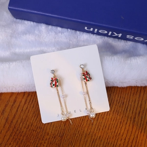 Detail view of asymmetric Christmas drop earrings with red enamel gift box and pearls
