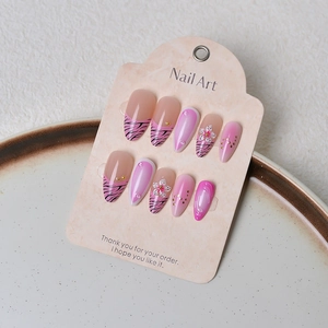 Détails de faux ongles rose zébré avec fleurs 3D et points dorés élégants