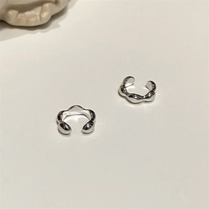 Detailed close-up of polished silver ear cuffs with sleek wave and bean pod design